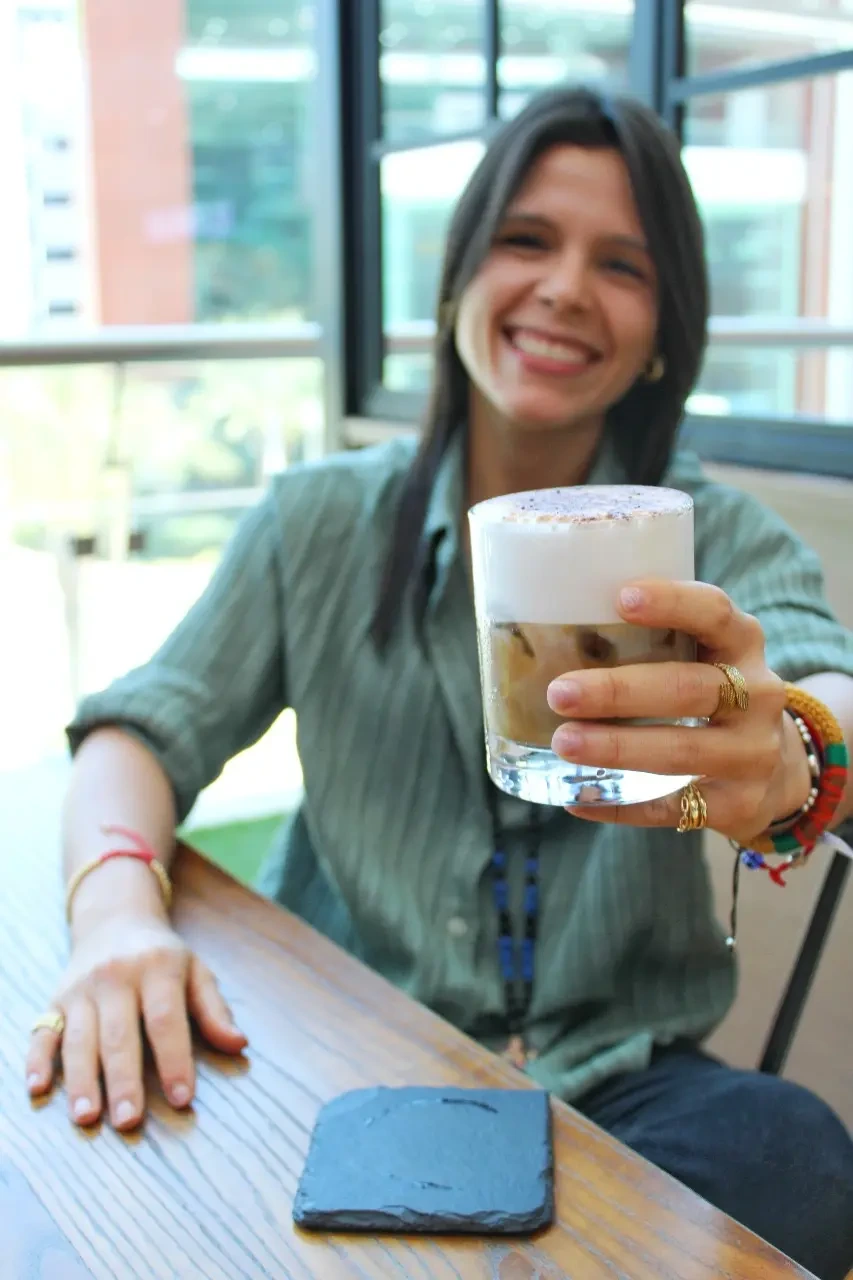 Gaby sonríe mientras acerca una taza de café.