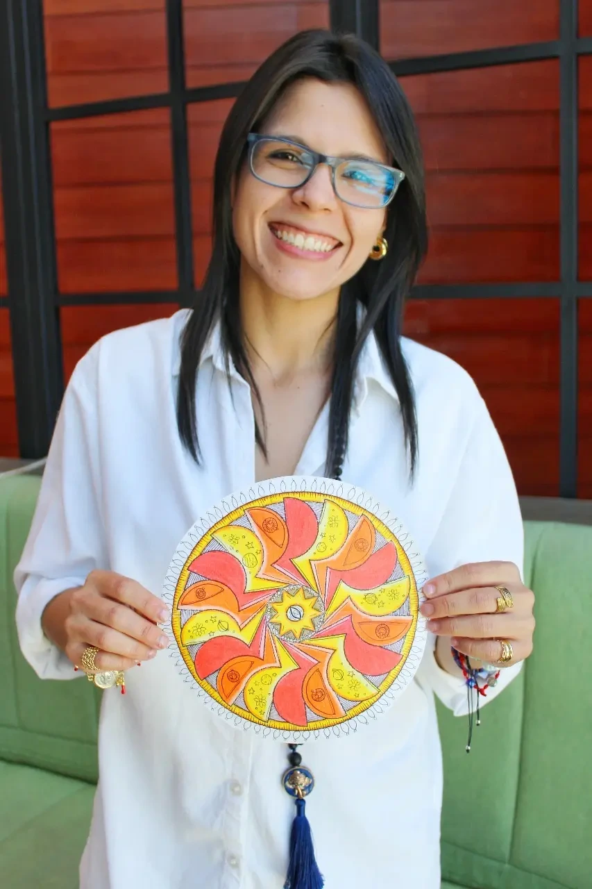 Gaby sostiene una ilustración circular de colores vivos.